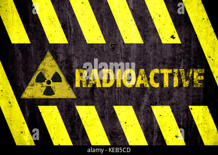Radioaktivität (ionisierende Strahlung) Gefahrensymbol und Wort mit gelben und schwarzen Streifen malte auf eine massive Betonwand mit rustikalen Textur backgroun Stockfoto