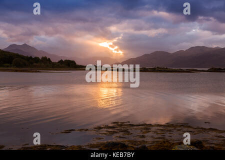 Dramatische dawn Licht und Sonnenstrahlen an ornsay Leuchtturm auf der Insel Eilean Sionnach aus der Halbinsel Sleat, Isle of Skye, Highland, Schottland, UK Stockfoto