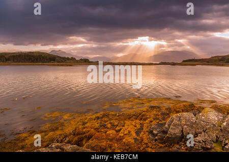 Dramatische dawn Licht und Sonnenstrahlen an ornsay Leuchtturm auf der Insel Eilean Sionnach aus der Halbinsel Sleat, Isle of Skye, Highland, Schottland, UK Stockfoto