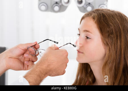 Nahaufnahme von einem Optiker Helfen lächelnde Mädchen mit neuen Brillen Stockfoto