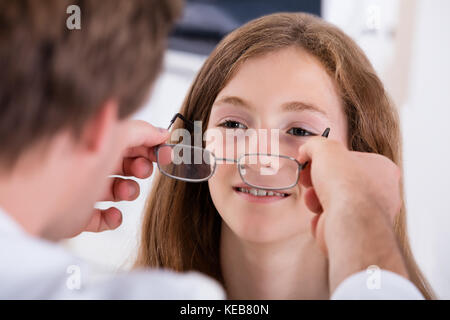 Nahaufnahme von einem Optiker Helfen lächelnde Mädchen mit neuen Brillen Stockfoto