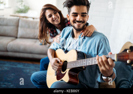 Jungen gutaussehenden Mann Gitarre spielen für seine Freundin Stockfoto