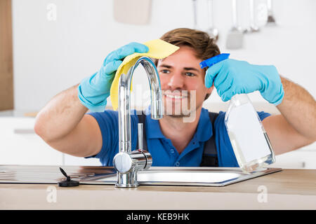Smiling Young Male Waschfacette Mit Lappen Und Waschmittel Sprühflasche Stockfoto