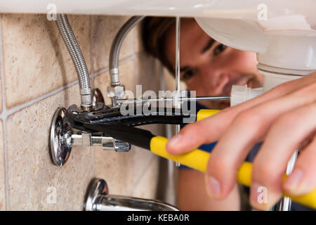 Nahaufnahme der männlichen Klempner Einbau Spüle mit einem Schraubenschlüssel Stockfoto
