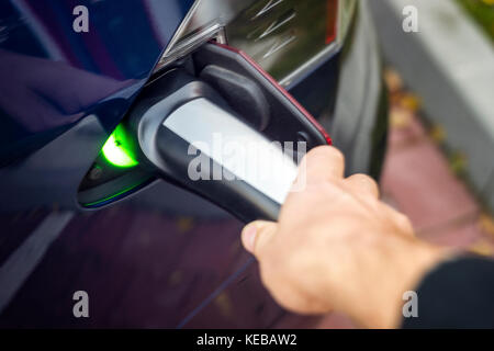 Der Mann der Linken Hand mit modernen elektrischen Auto Ladegerät anschließen. Stockfoto