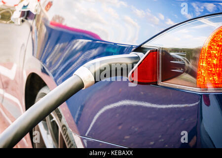 Moderne elektrische blaues Auto gesteckt zu Ladestation. Stockfoto