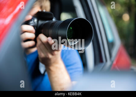 Privatdetektiv Sitzen im Auto Fotografieren mit SLR-Kamera Stockfoto