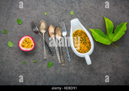 Frische Passionsfrüchte auf dunklem Stein Hintergrund. Leidenschaft Obst und Saft mit Pfeffer Minze. Gesundes essen Hintergrund Konzept. Stockfoto