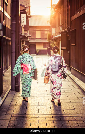 Zwei Japanerinnen tragen Kimonos zu Fuß heim in den Sonnenuntergang in Gion, Kyoto Stockfoto