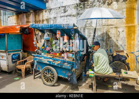 Jakarta, Indonesien - 3. März, 2017: lokale Mann sitzt neben seinem kleinen Markt Trolley, Verkauf von Hardware Werkzeuge und Produkte Stockfoto