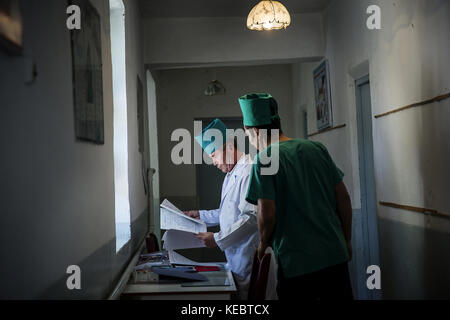 Beshkent, Kirgisistan. Oktober 2016. Ärzte Abid Madaliev, links, und Asadschon Polvonow in einer Dorfklinik in Beshkent, Kirgisistan. Die Klinik verlässt sich auf Wasser aus einem nahe gelegenen Bewässerungskanal namens aryk. Das Wasser wird gekocht, bevor es den Patienten gegeben oder in medizinischen Behandlungen verwendet wird, da es durch Bakterien kontaminiert wird, die Hepatitis und andere wasserübertragene Krankheiten verursachen. Die Einheimischen hoffen und planen ein Infrastrukturprojekt, um sauberes Wasser in ihre Häuser zu bringen. In Dörfern in ganz Kirgisistan (Zentralasien) sind antiquierte Wasserversorgungssysteme und Infrastruktur vorhanden Stockfoto