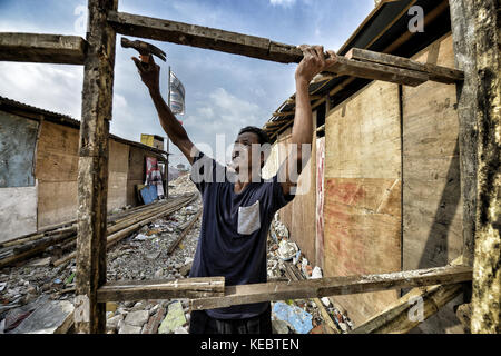 Jakarta, Java, Indonesien. August 2016. Die Menschen weigern sich zu gehen und versuchen, ihre Häuser mit Resten von Holz und Plastik in der Nachbarschaft Pasar Ikan in Jakarta wiederaufzubauen. Im April letzten Jahres stürmten Hunderte von Soldaten und Polizisten Pasar Ikan, ein historisches Fischerviertel nördlich von Jakarta, und machten alles in Trümmer. Wo es Backsteinhäuser gab, jetzt gibt es Berge von Schutt und Zelten. Die Einwohner zögern, die Nachbarschaft zu verlassen und weigern sich, in die von den Behörden gewährten Schutzhütten zu ziehen, weil sie behaupten, sie könnten sich das nicht leisten Stockfoto