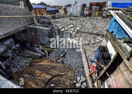 Jakarta, Java, Indonesien. August 2016. Die Menschen weigern sich zu gehen und versuchen, ihre Häuser mit Resten von Holz und Plastik in der Nachbarschaft Pasar Ikan in Jakarta wiederaufzubauen. Im April letzten Jahres stürmten Hunderte von Soldaten und Polizisten Pasar Ikan, ein historisches Fischerviertel nördlich von Jakarta, und machten alles in Trümmer. Wo es Backsteinhäuser gab, jetzt gibt es Berge von Schutt und Zelten. Die Einwohner zögern, die Nachbarschaft zu verlassen und weigern sich, in die von den Behörden gewährten Schutzhütten zu ziehen, weil sie behaupten, sie könnten sich das nicht leisten Stockfoto