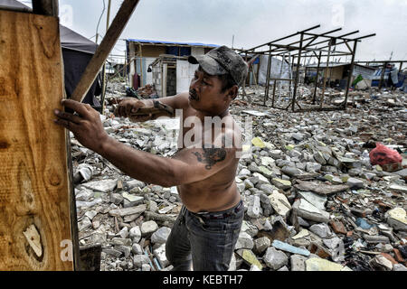 Jakarta, Java, Indonesien. August 2016. Ein Mann wird gesehen, wie er ein Haus nach der Räumung und dem Abriss des Pasar Ikan Stadtviertels von Jakarta baute. Im April letzten Jahres stürmten Hunderte von Soldaten und Polizisten Pasar Ikan, ein historisches Fischerviertel nördlich von Jakarta, und machten alles in Trümmer. Wo es Backsteinhäuser gab, jetzt gibt es Berge von Schutt und Zelten. Die Einwohner zögern, die Nachbarschaft zu verlassen und weigern sich, in die von den Behörden gewährten Schutzhütten zu ziehen, weil sie behaupten, sie könnten sich diese nicht leisten. Sie sind Räumungen wi Stockfoto