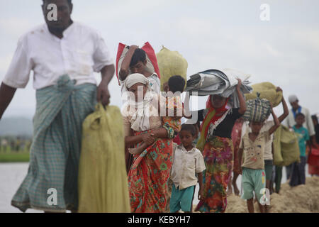 Ukhiya, Cox's Bazar, Bangladesch. 19 Okt, 2017. rohingya Muslime, die vier Tage in der offenen nach Überquerung von Myanmar in Bangladesch verbracht, tragen ihre Kinder und Habseligkeiten nach durften sie auf dem Weg zu einem Flüchtlingslager zu gehen, an der Anjuman para, ukhiya, Bangladesh, 19. Oktober 2017. Mehr als 580.000 Flüchtlinge in Bangladesch angekommen sind seit Aug. 25, wenn Myanmar Sicherheitskräfte begann eine Politik der verbrannten Erde Kampagne gegen rohingya Dörfer. Credit: zuma Press, Inc./alamy leben Nachrichten Stockfoto