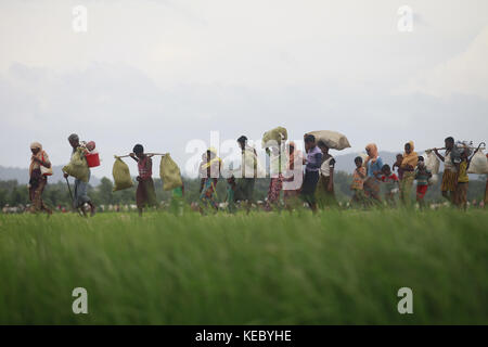 Ukhiya, Cox's Bazar, Bangladesch. 19 Okt, 2017. rohingya Muslime, die vier Tage in der offenen nach Überquerung von Myanmar in Bangladesch verbracht, tragen ihre Kinder und Habseligkeiten nach durften sie auf dem Weg zu einem Flüchtlingslager zu gehen, an der Anjuman para, ukhiya, Bangladesh, 19. Oktober 2017. Mehr als 580.000 Flüchtlinge in Bangladesch angekommen sind seit Aug. 25, wenn Myanmar Sicherheitskräfte begann eine Politik der verbrannten Erde Kampagne gegen rohingya Dörfer. Credit: zuma Press, Inc./alamy leben Nachrichten Stockfoto