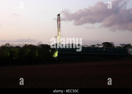 York, North Yorkshire, Großbritannien. Oktober 2017. Ein hydraulisches Fracking-Rig, das einige hundert Meter vor den Anti-Fracking-Protesten im Besitz von ''Third Energy'' ist, beginnt seine abendlichen Betriebslichter, während die Nacht über die Felder zieht.zwei Anti-Fracking-Demonstranten aus dem Anti-Fracking-Lager Kirby-Misperton in North Yorkshire wurden verhaftet, kurz nachdem sie eine 24-stündige Sperre für ein Holz beendet hatten Turm, der das Haupttor der Fracking Company ''Third Energy''' in North Yorkshire blockierte. Die Polizei von North Yorks übertraf die Zahl der Demonstranten, die sich gegen beide mit schweren Händen und Hinderungsmaßnahmen widersetzten Stockfoto