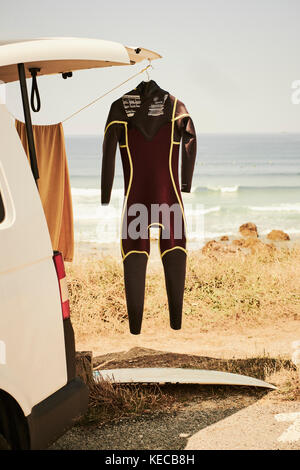 Ein Surfer van am Strand mit einem Neoprenanzug hängen draußen geparkt. Stockfoto