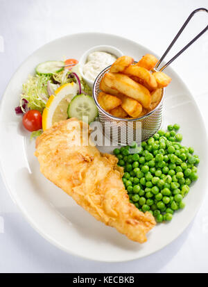 Fisch und Chips mit Erbsen und Salat auf einem weißen Teller Schuß von oben. Stockfoto