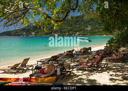 Die Seychellen, Mahe, Beau Vallon, Strand, Touristen auf Liegestühlen außerhalb H Resort Stockfoto