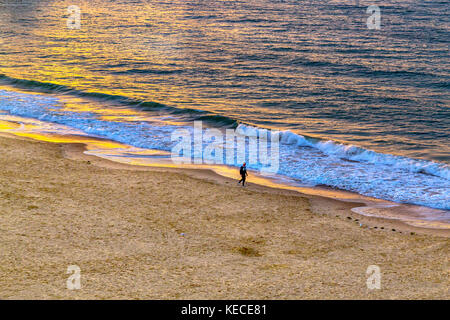 Ein Mann Spaziergänge entlang dem Strand von Bournemouth in der Morgendämmerung Stockfoto