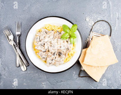 Bandnudeln mit Pilzen und cremige Soße, Parmesan über konkrete strukturierten Hintergrund Stockfoto