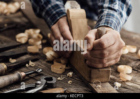 Tischler arbeiten in seiner Werkstatt, er ist die Glättung ein Holzbrett mit einem Planer, Tischlerei, Schreinerei, Holzverarbeitung und Handwerkskunst Konzept Stockfoto