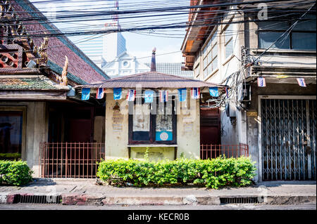 Eine alte Art Thai House sitzt vor einem modernen Wolkenkratzer in einer ruhigen Straße in Bangkok, Thailand, South East Asia. Stockfoto