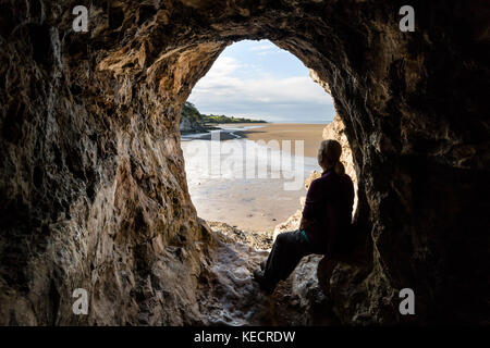 Wanderer genießen den Blick von der Innenseite der Bucht Höhle über den Sand der Morecambe Bay, Silverdale, Lancashire, Großbritannien Stockfoto