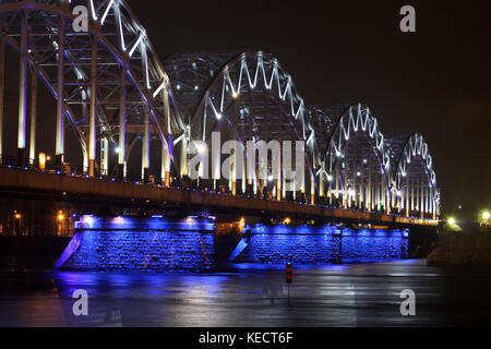 Railway Bridge bei Nacht mit weiß-blauer Beleuchtung, Reflexion in den Fluss. Stockfoto