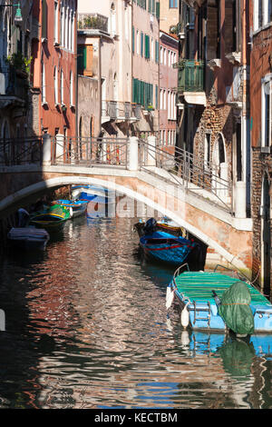 Malerische schmale Kanal in Dorsoduro bei Sonnenuntergang, Venedig, Italien mit bunten Boote unter einer Brücke und alte traditionelle Häuser Stockfoto