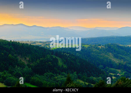 Weites panorama Blick auf nebligen Tal im Eulengebirge mit Silhouette der Sudeten Berge in der Abenddämmerung. Landschaft Landschaft im Südwesten Polens. Stockfoto