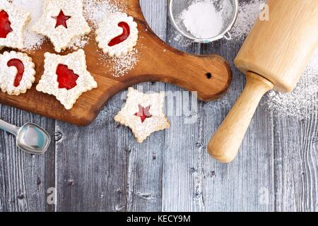 Weihnachten backen overhead Szene auf einem Holz- Hintergrund mit Linzer Marmelade cookies Stockfoto