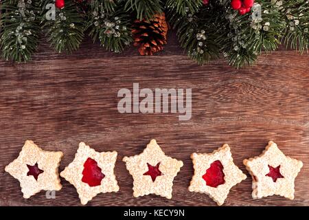 Weihnachten backen Doppel Grenze auf einer hölzernen Hintergrund mit Niederlassungen und Marmelade cookies Stockfoto