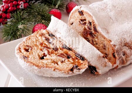 Traditionelle hausgemachte Stollen Dessert mit geschnittenen Scheiben auf einen Teller mit Weihnachtsdekor Stockfoto