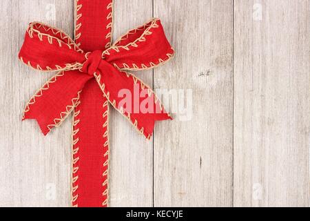 Rustikale red christmas bogen und farbband Seite, oben Blick auf einen alten weißen Holz Hintergrund Stockfoto