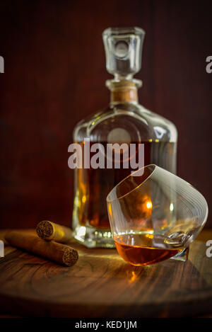 Zwei Zigarren, ein Glas und eine Flasche Rum auf einer hölzernen Oberfläche Stockfoto