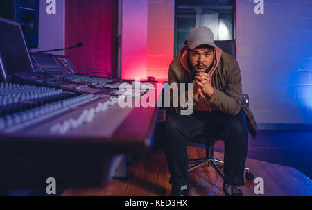 Junger Mann sitzt von Audio Mischpult in Sound Recording Studio. Männliche Komponisten sitzen durch Sound Mixing Console. Stockfoto