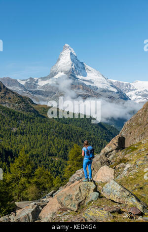 Wanderer steht auf Felsen und in die Ferne schaut, auf der Rückseite die schneebedeckten Matterhorn, Wallis, Schweiz Stockfoto