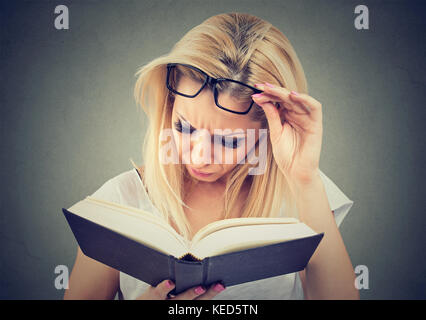 Frau mit Brille leiden unter Überanstrengung der Augen nach dem Lesen ein Buch Stockfoto