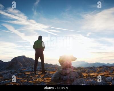 Touristische in grün Outdoor Jacke auf Rocky View Point. gestapelt gebrochene Steine in Pyramide. Nationalpark Alpen Park in Österreich Deutschland Grenze. sonnigen Herbst Stockfoto
