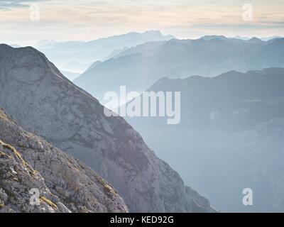 Einen spektakulären Blick auf die Berge Silhouetten und nebligen Täler. misty Erwachen der schönen Fee Tal. Gipfel der Felsen cremige Nebel Wolken schneiden. Stockfoto