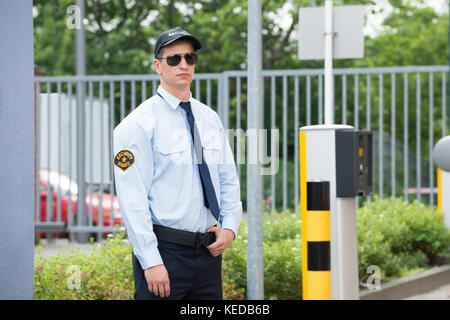 Junge männliche Security Guard stand neben dem Auto Parken der Maschine Stockfoto