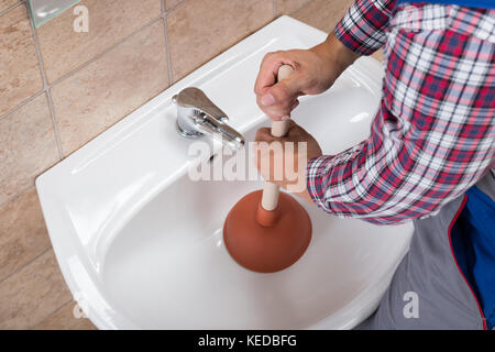 Nahaufnahme eines Klempners mit Kolben im Waschbecken im Bad Stockfoto