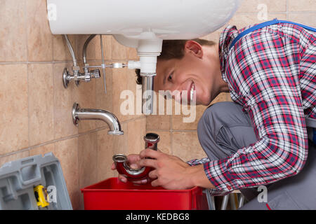 Glückliche junge männliche Klempner Installation Waschbecken im Badezimmer Stockfoto