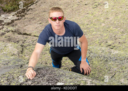 Eine ernsthafte Suche Bergsteiger steht am Fuß einer Felswand Stockfoto