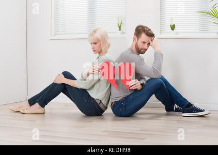 Traurig Paar zurück zu sitzen zurück halten roten gebrochenes Herz Stockfoto