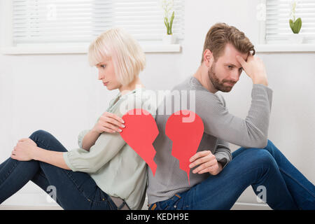 Traurig Paar zurück zu sitzen zurück halten roten gebrochenes Herz Stockfoto