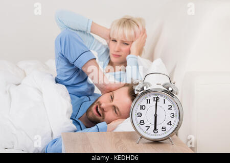 Junges Paar von Wecker im Schlafzimmer zu Hause geweckt erschöpft Stockfoto