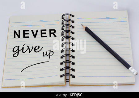 Motivierende Worte Gib dich nie auf einer Seite eines geöffneten Notebook mit Bleistift daneben geschrieben. Stockfoto